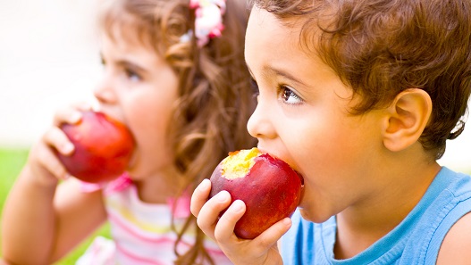 Foto de dos niños comiendo manzanas rojas